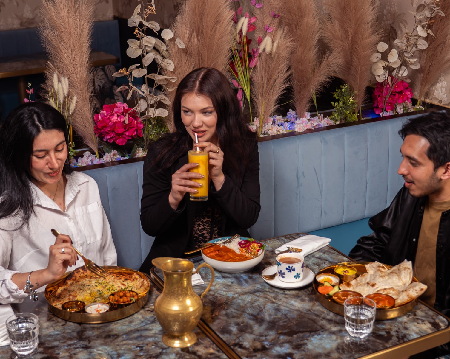 Three guests sharing Indian lunch and drinks at Desi Lounge in Vancouver